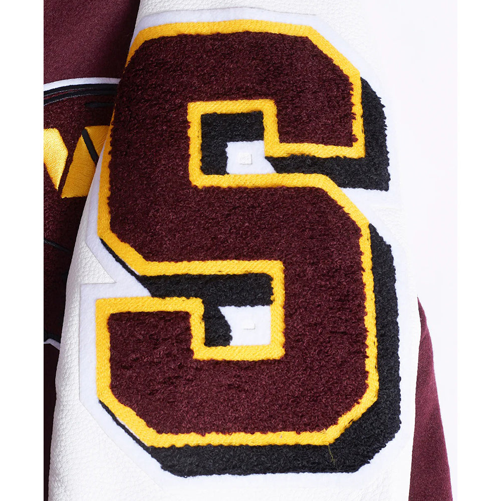 Close-up of a maroon 'S' logo with yellow border on a sports jersey.