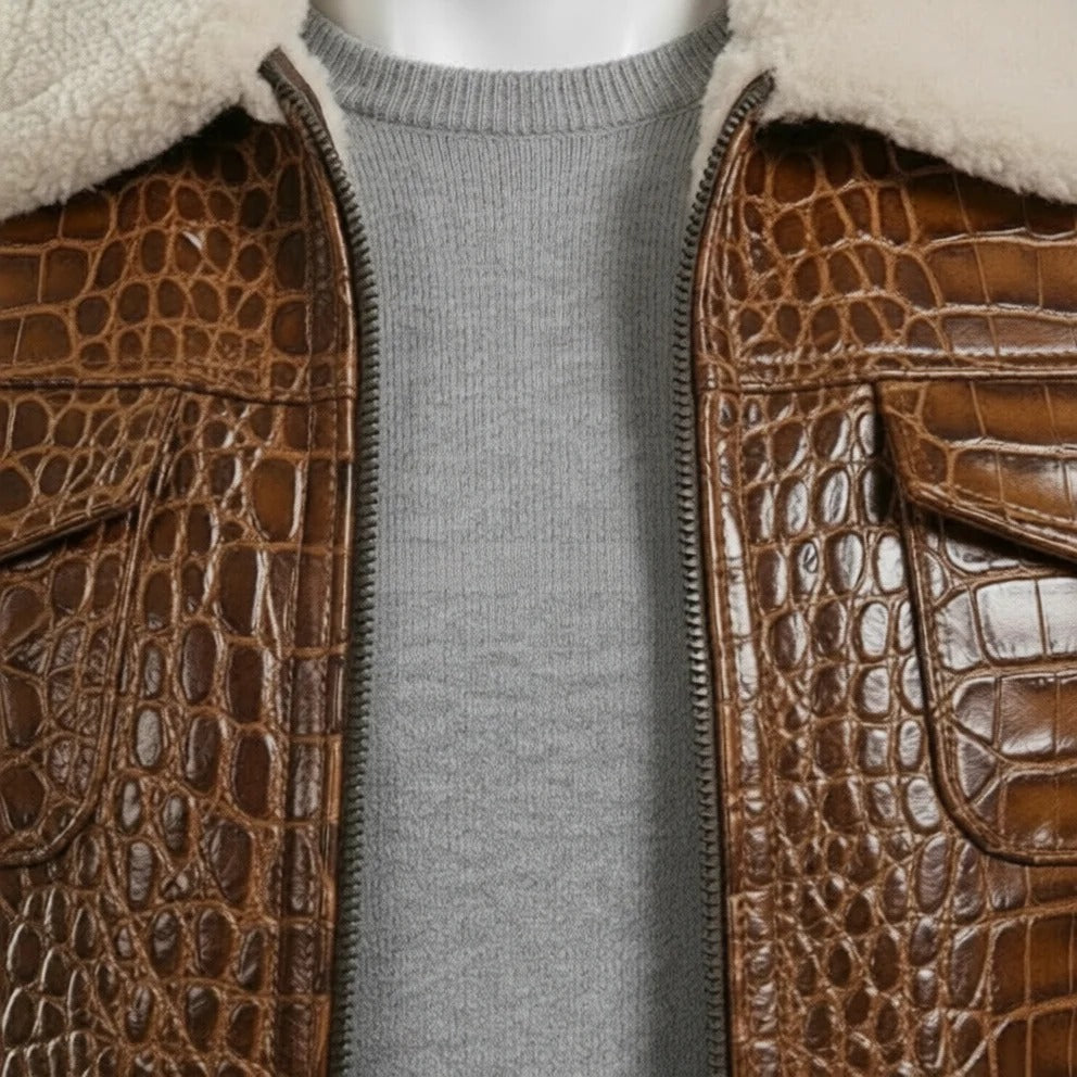 A close-up of a brown crocodile-embossed leather jacket with a cream shearling-style collar, worn over a gray knit sweater on a mannequin.